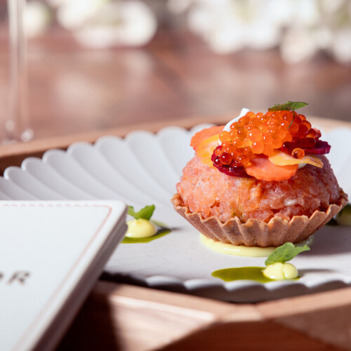 Tartaletka z łososiem i kawiorem na jasnym talerzu.