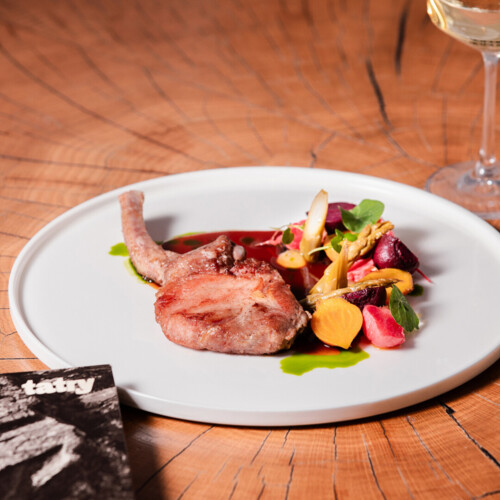 Elegancko ułożony plaster mięsa z sosem i warzywami.