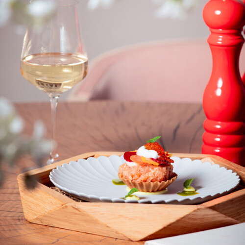 Tartaletka na białym talerzu i czerwony ręczny młynek do pieprzu.