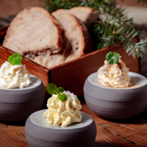 Kromki chleba w pojemniku i trzy porcje masła.