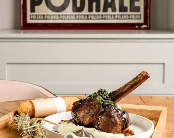 Widok na pieczone mięso podane na talerzu i drewnianej tacy.