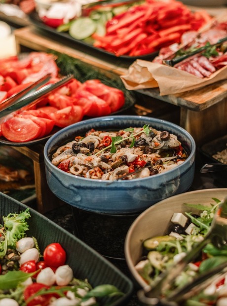 Hotelový bufet se salátovým barem: čerstvé plátky rajčat, směs salátů, antipasti, olivy, semínka a kleště