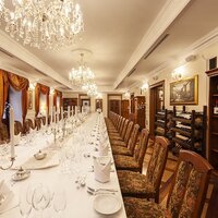 Elegancka sala bankietowa z długim białym stołem, kryształowymi żyrandolami, świecami i regałami z win - idealna na wesele