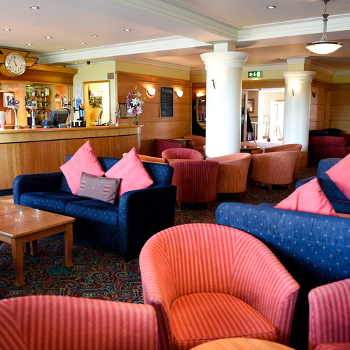 Cozy hotel lounge with bar and games room area serving bar snacks