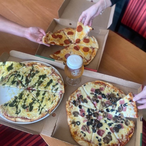Three large pizzas in open boxes, pepperoni, mushroom with olives, and pesto cheese, hands grabbing slices around frothy beer.