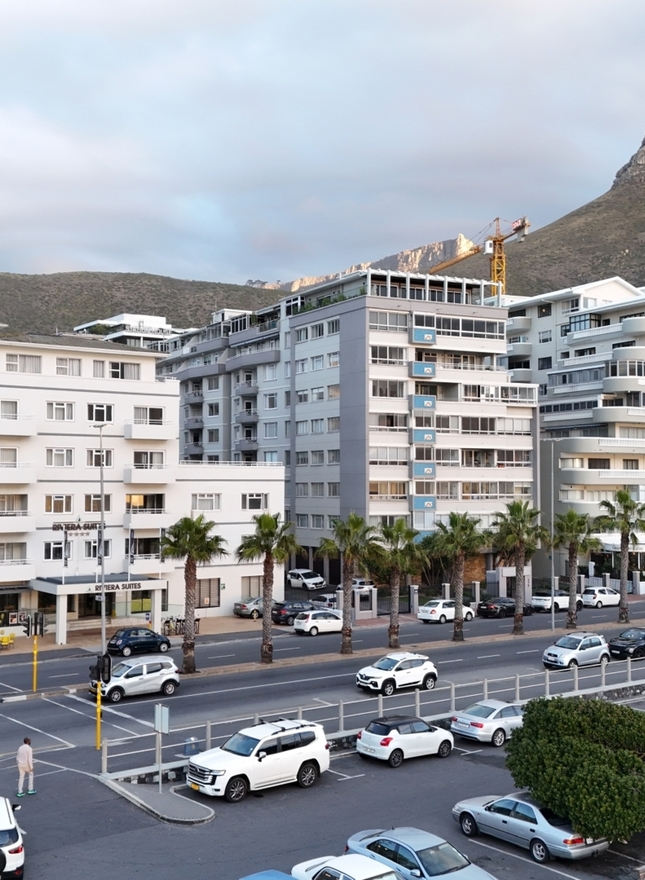 Riviera Suite with balconies, palm-lined promenade, street cafés, parking and mountain backdrop.