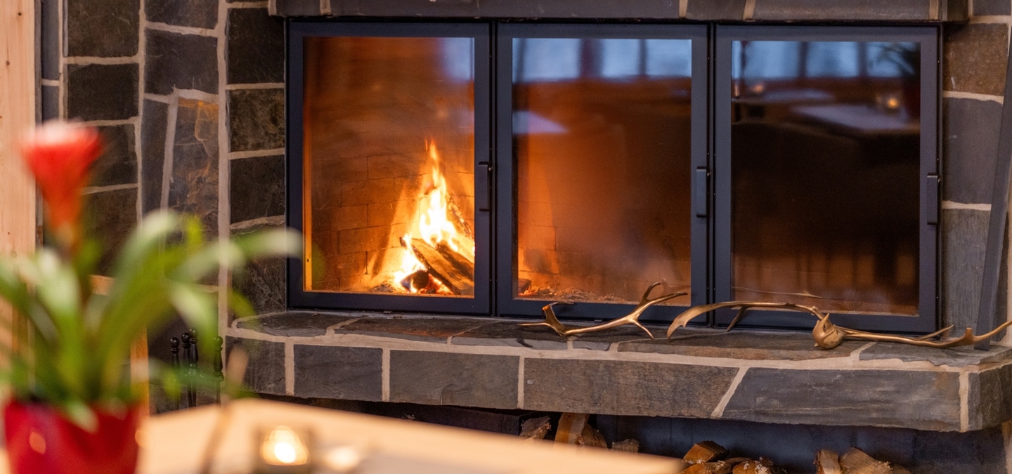 Cozy stone fireplace with wood storage below and antler decor in a warm hotel lounge atmosphere