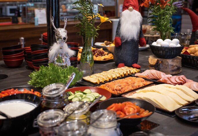 Aamiaisbuffet, jossa on savulohta, leikkeleitä, juustoja ja joulutonttukoristeita