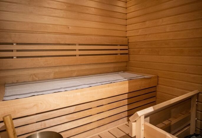 Traditional Finnish sauna with wooden benches, sauna heater, bucket and ladle at Santa Claus Holiday Village in Rovaniemi, Finnish Lapland