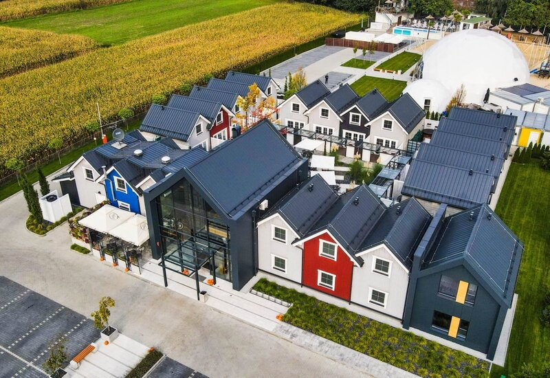 Butikowy hotel z kolorowymi domkami, przeszklonym lobby, patio, basenem i białą kopułą przy polu kukurydzy.