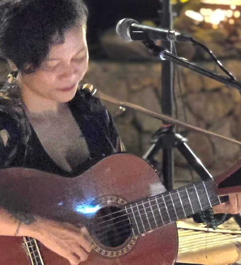 Live acoustic guitar performance creating a cozy, intimate evening ambiance at an outdoor hotel lounge or bar