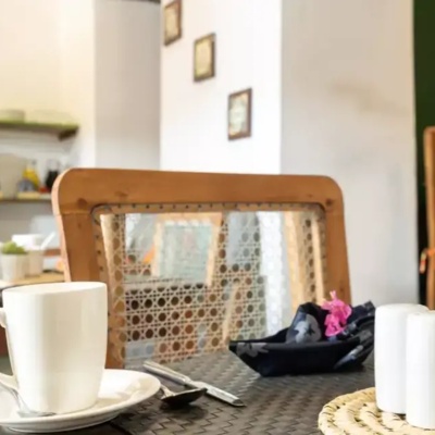 Cozy hotel dining area with woven cane chairs, white coffee cups, a succulent plant, and soft natural lighting