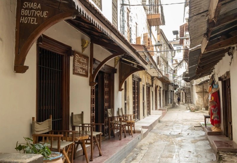 Shaba Boutique Hotel entrance with wooden chairs and tables along a narrow, historic stone-paved street lined with traditional buildings