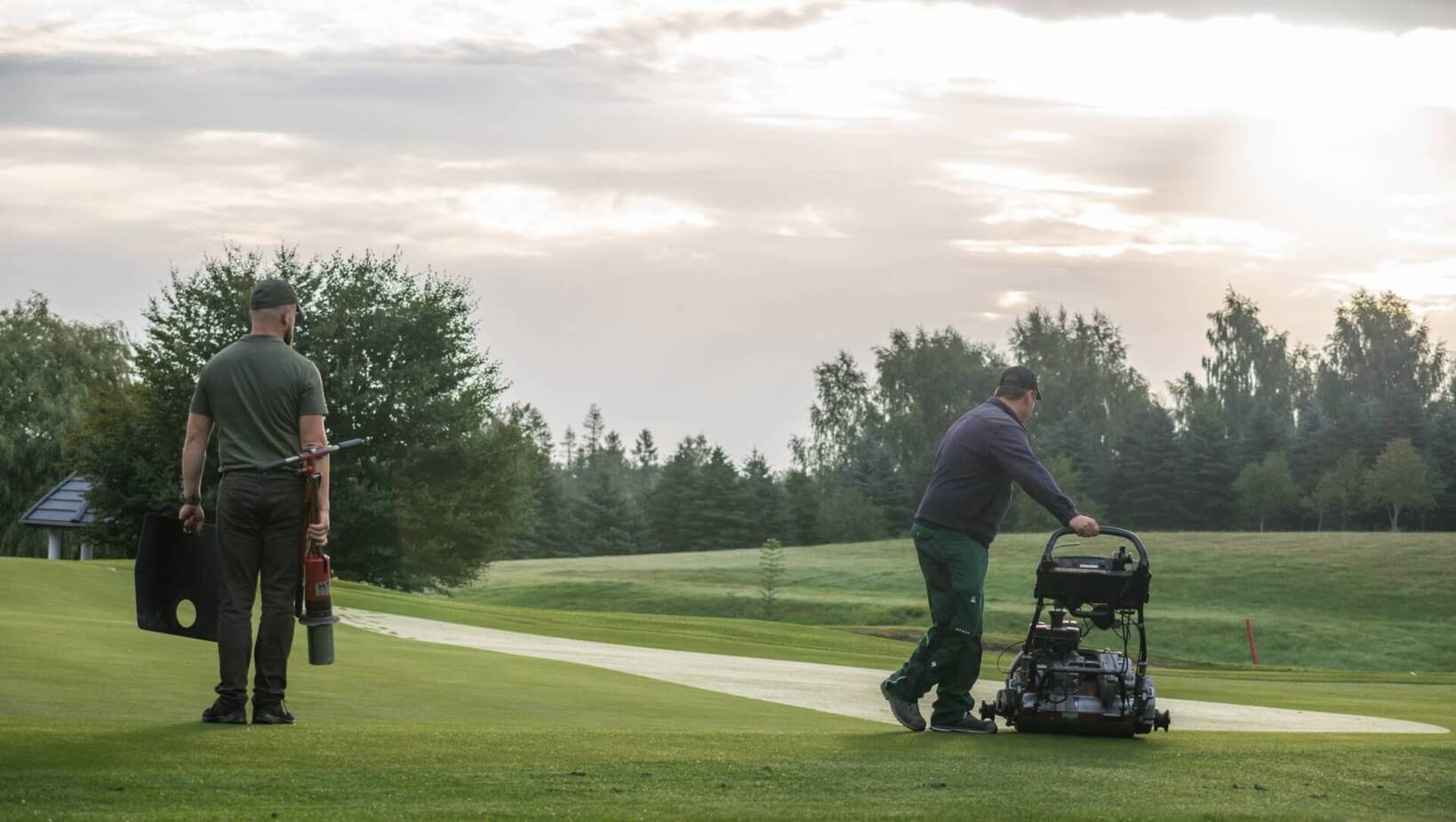 Pracownicy utrzymujący pole golfowe: koszenie greenu, pielęgnacja murawy i obsługa maszyny