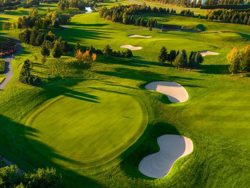 Widok na zadbane pole golfowe o gładkich greenach, piaskowych bunkrach, alejkach i drzewach — idealne dla gości resortu.