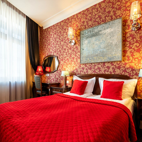 Bedroom with a double bed, red bedspread and decorative wallpaper in Junior Suite Deluxe Red