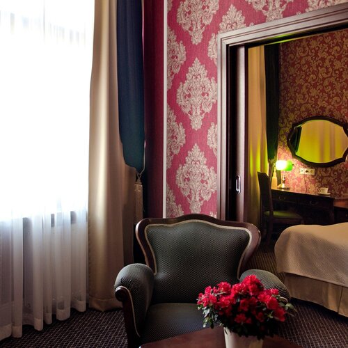 Sitting area with an armchair and access to the bedroom in Junior Suite Deluxe Red at SleepWalker Boutique Suites in Wroclaw