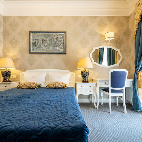 Bedroom with a double bed, blue bedspread, dressing table and mirror in Junior Suite Deluxe Blue