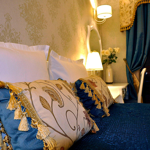 Decorative cushions, blue bedspread, bedside lamp and navy curtains in Junior Suite Deluxe Blue