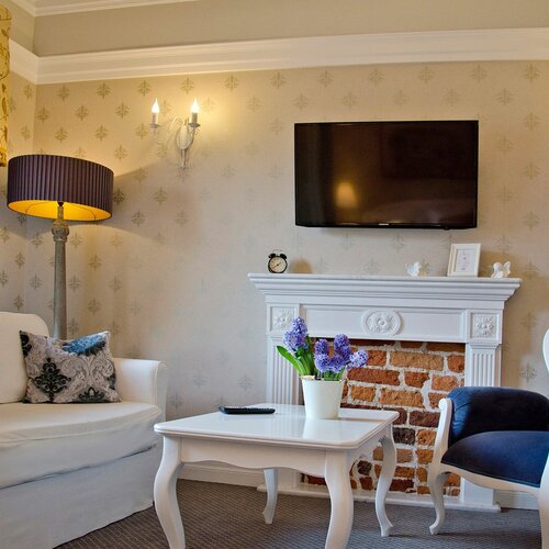 Living room with a sofa, armchair, coffee table and decorative brick fireplace in Junior Suite Deluxe Blue