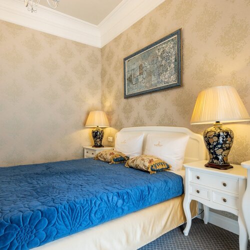 Bedroom with a double bed, blue bedspread and bedside lamps in Junior Suite Deluxe Blue