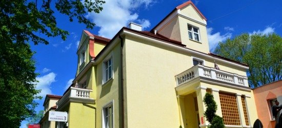 Sanatorium Kujawianka — żółty pensjonat z czerwonym dachem, balkonami, schodami przy wejściu i skalnym ogrodem.