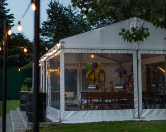 Namiot bankietowy udekorowany na 40. urodziny, z kolorowymi balonami i nastrojowym oświetleniem na świeżym powietrzu.