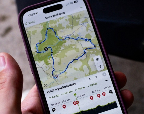 Smartfon z aplikacją pokazującą trasę rowerową w okolicy Resortu Stara Wieś i odległościami na tle mapy.