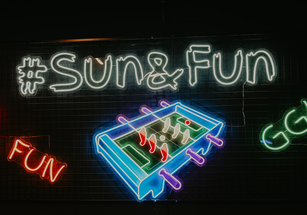 #SUN&FUN neon sign above colorful foosball neon, lively bar and game-room vibe
