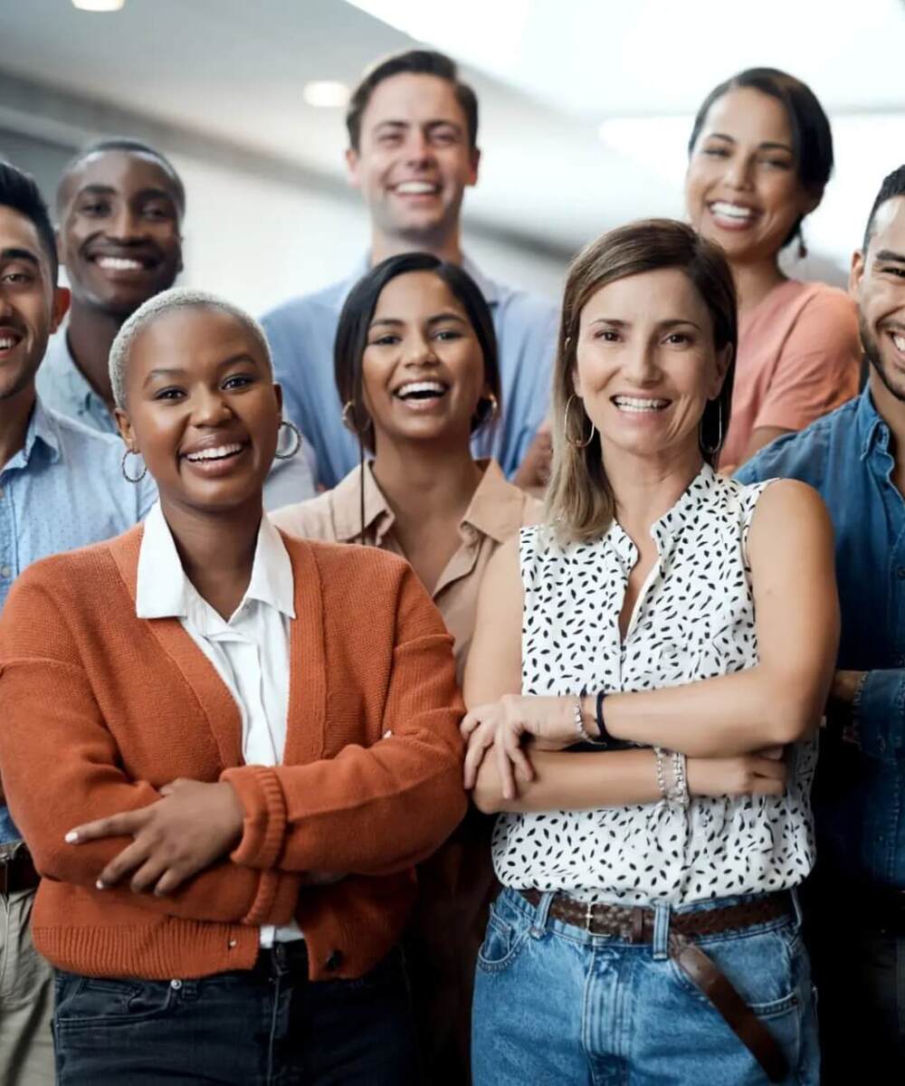 Smiling diverse hotel team standing in bright modern lobby, casual business attire suggesting front-desk, guest services and concierge.