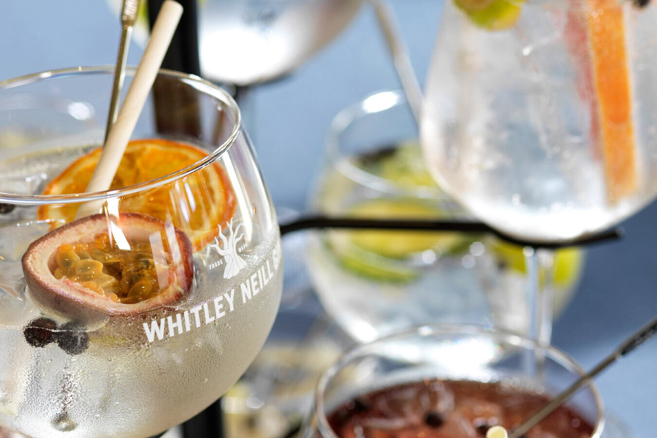 Tiered stand of chilled stemmed cocktails garnished with passionfruit, dried orange, citrus, ice and berries