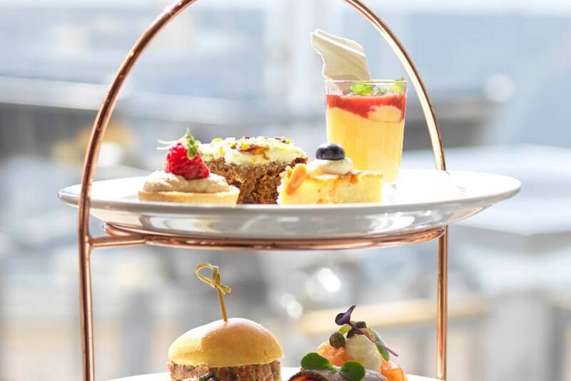 Three-tier copper stand with pastries (cake, tart, layered mousse) and savory bites: mini slider and smoked salmon canapé
