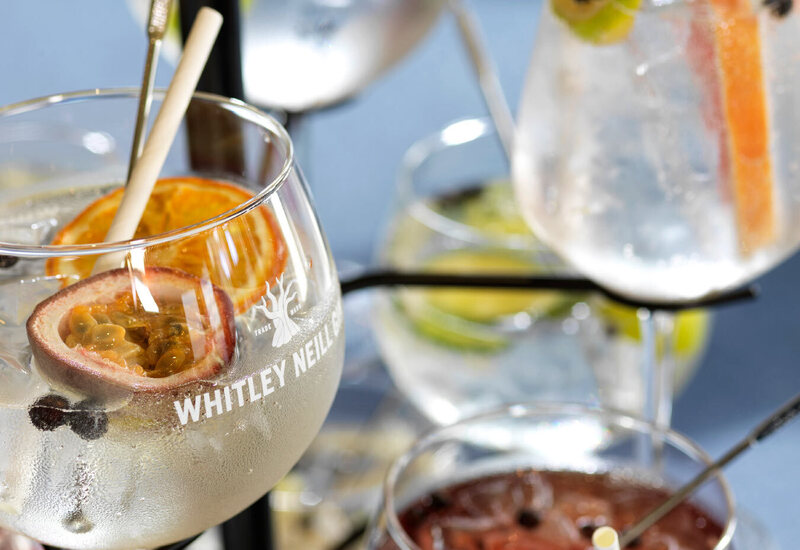 Tiered stand of chilled stemmed cocktails garnished with passionfruit, dried orange, citrus, ice and berries