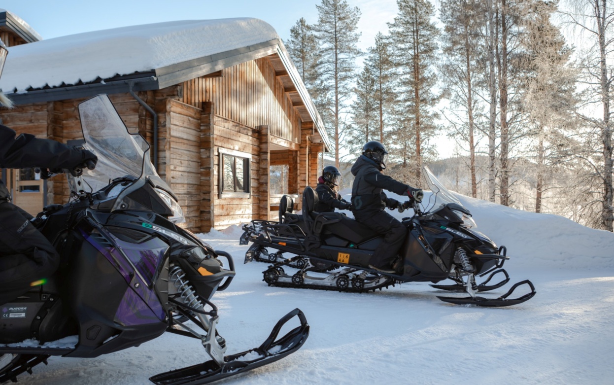 People on electric snowmobiles getting ready for a snow safari.