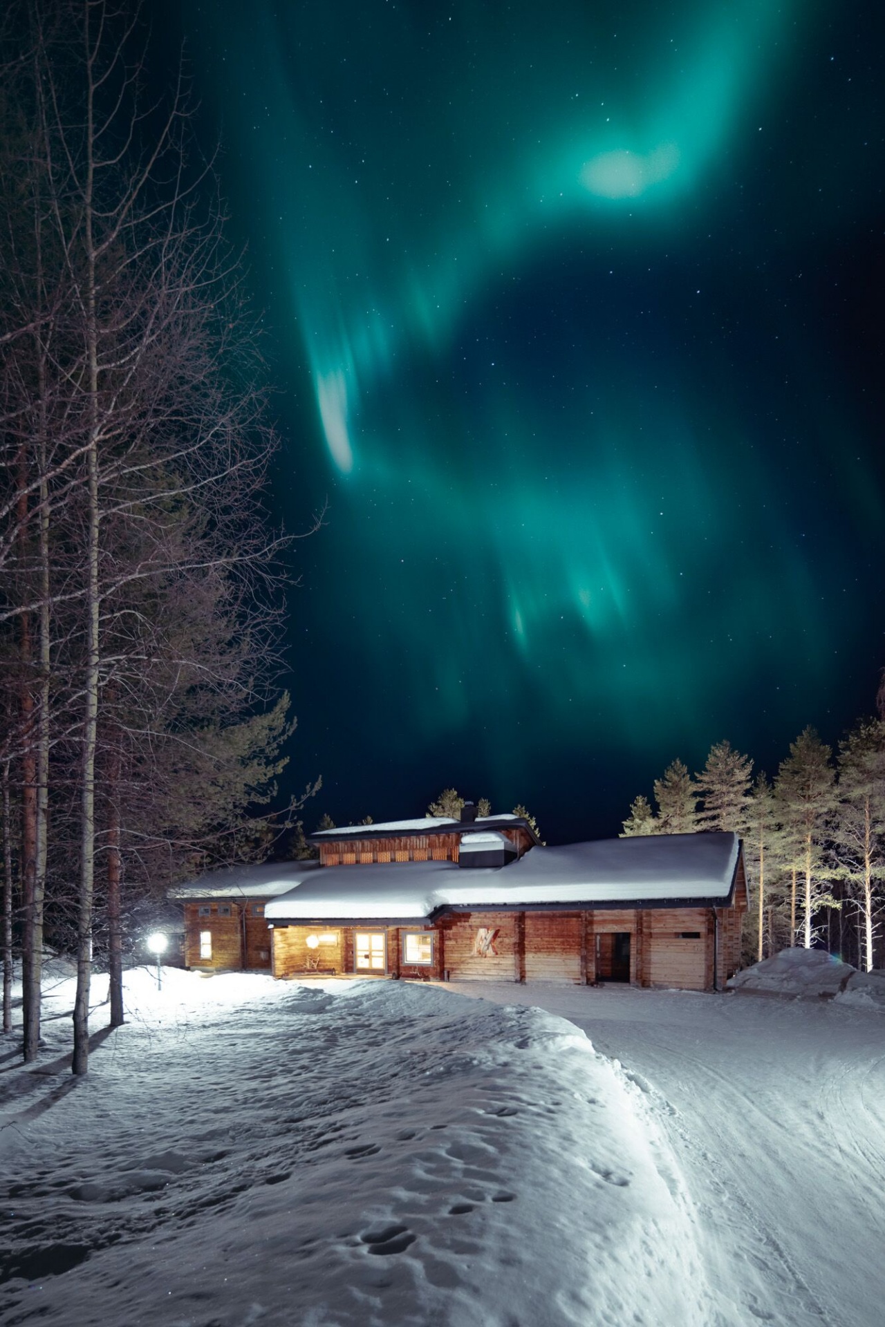 Northern lights descending upon the wooden lodge of the Sunday Morning Resort.