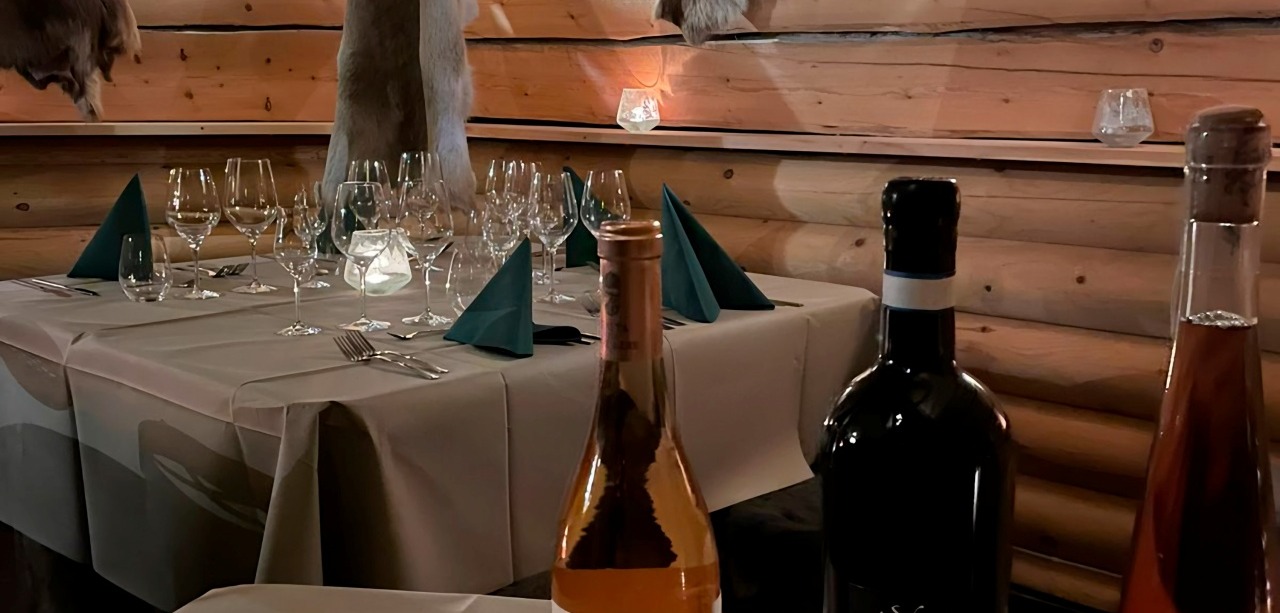 2 tables: one with bottles of exclusive wine and one with wine glasses and skillfully folded napkins