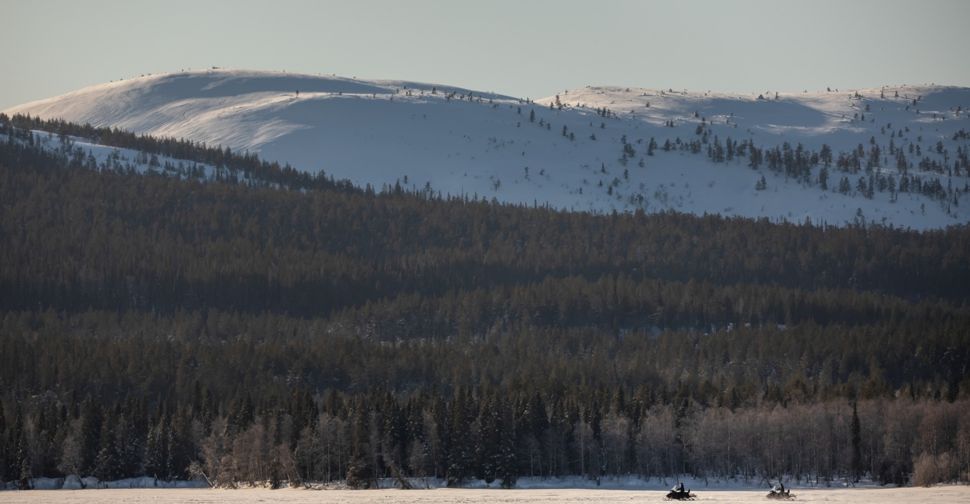 Two people in the distance eSleding into the wilderness.