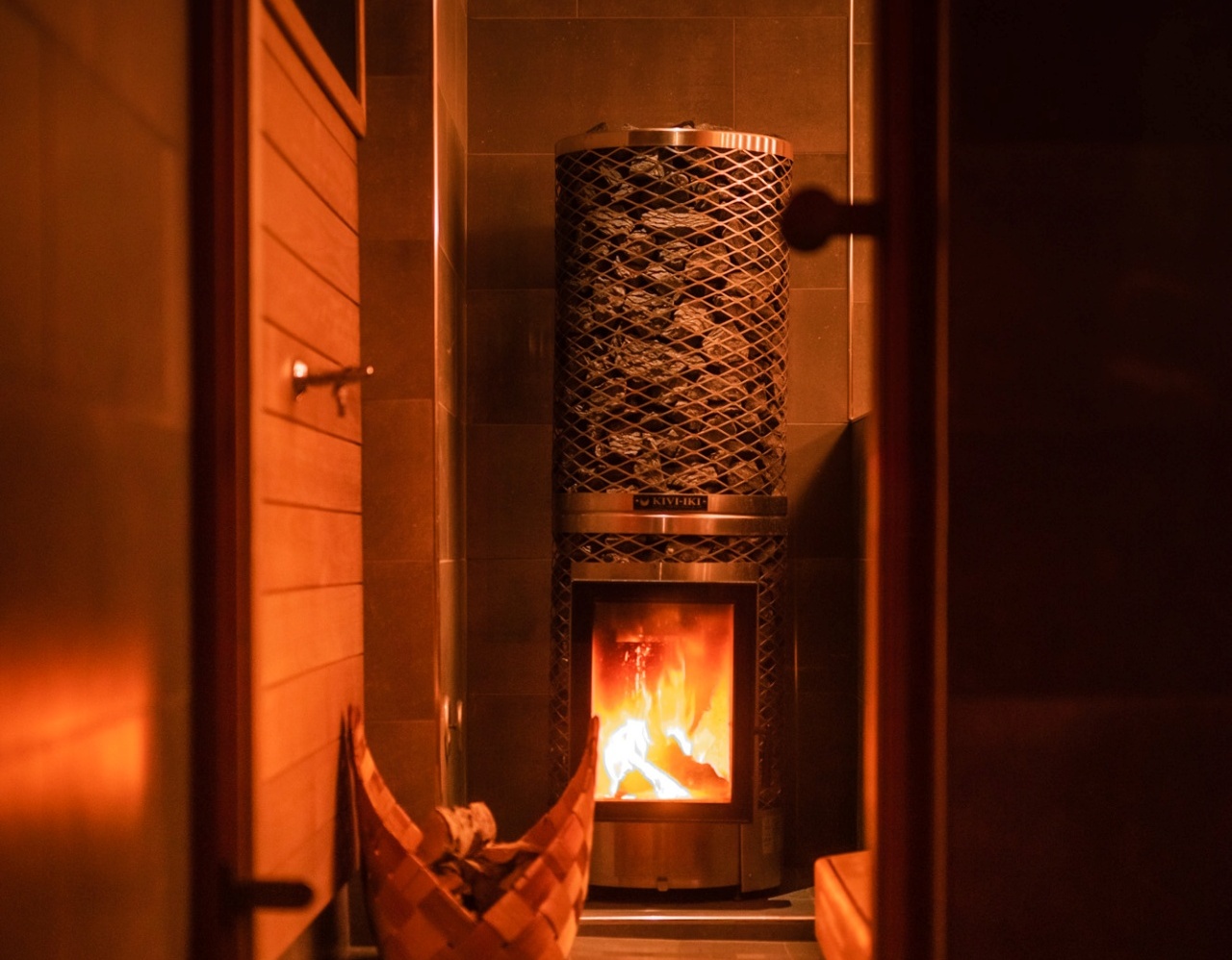 Poêle de sauna chaud avec pierres chauffantes et panier en bois dans une salle de sauna en bois chaleureuse