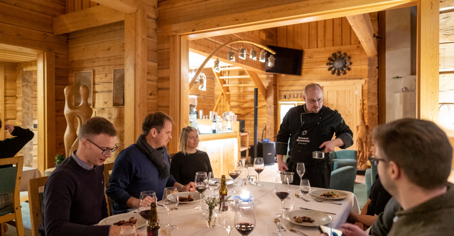 Apartment guests sitting at their table, while the chef serves traditional nordic cuisine.