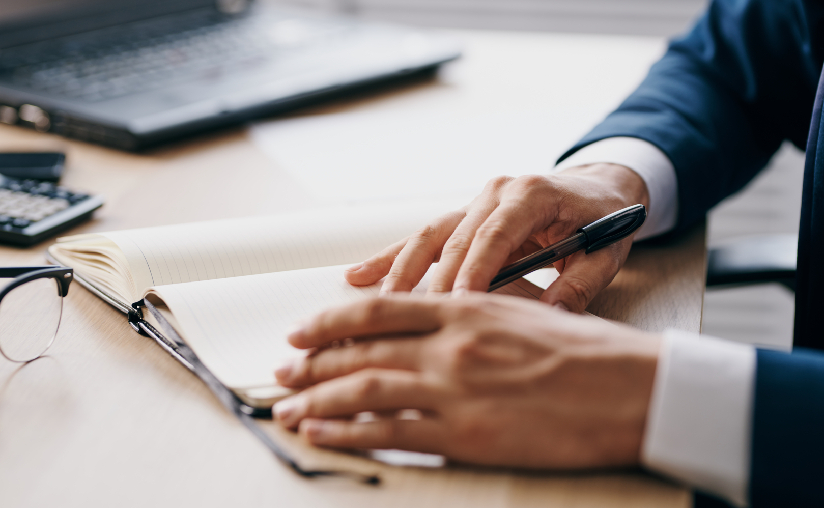 A close-up of male hands writing in a notepad.