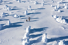 A group of people hiking through a vast snow dessert.