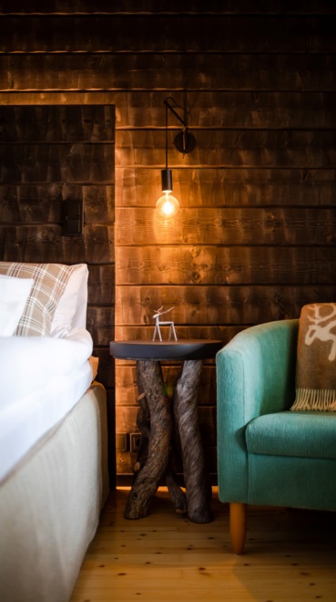 A timber bedroom illuminated by a single light bulb casting warm light on the furniture.