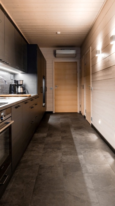 Kitchen space in the apartment. Stone tiles on the floor, wooden walls illuminated by bright light.