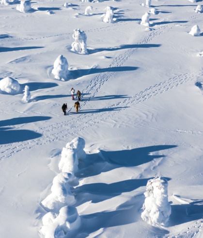 A group of people hiking through a vast snow dessert.