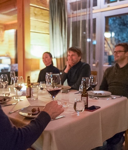 Resort guests sitting ad the table, drinking wine and enjoying a Christmas dinner.