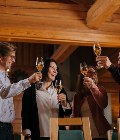 Four people raising toasts in a wooden lodge.