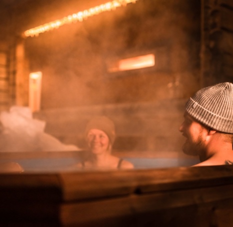 Three people covered by steam, enjoying their time in the hot tub.