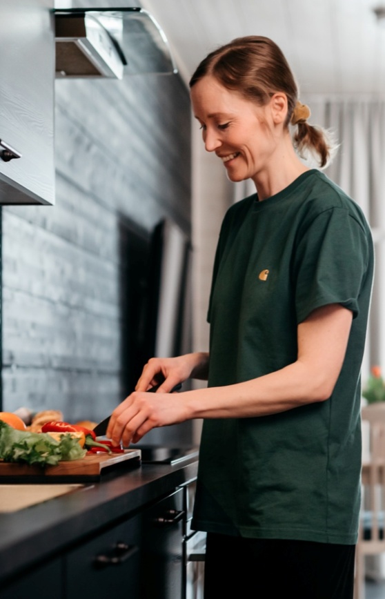 A female guest chopping vegetables in the kitchen and smiling.