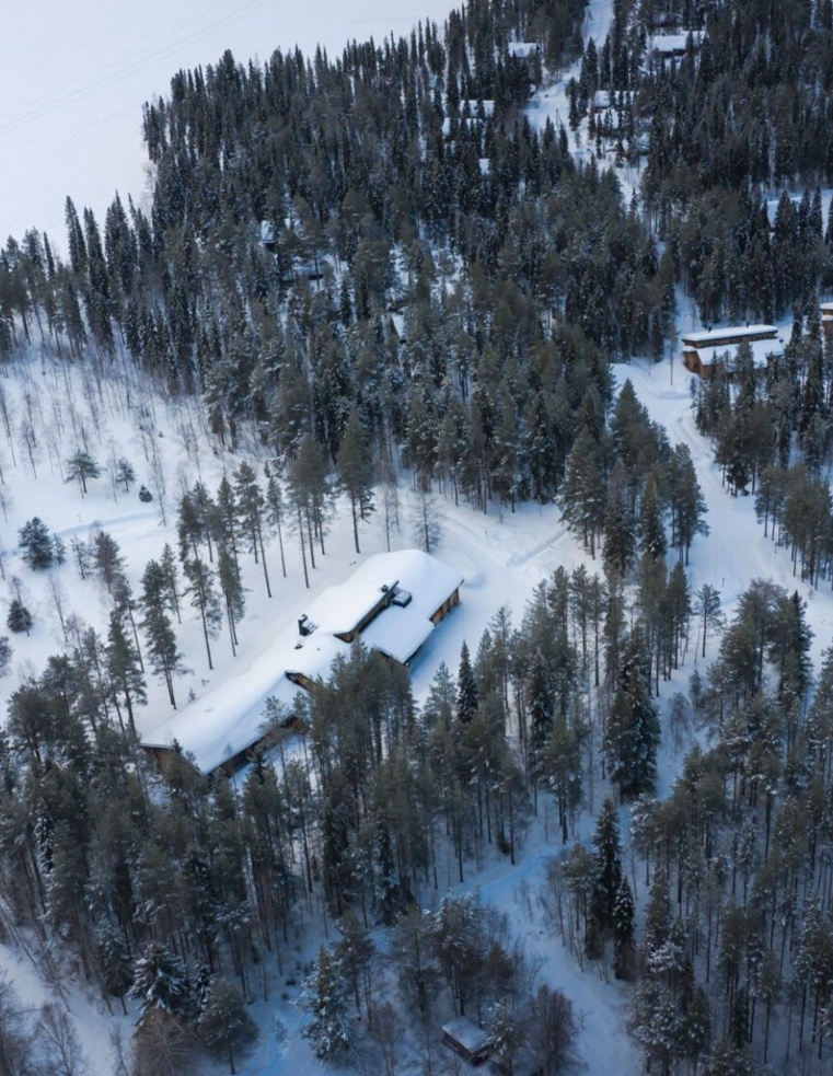 A snow-covered lodge visible from above and surrounded by trees.