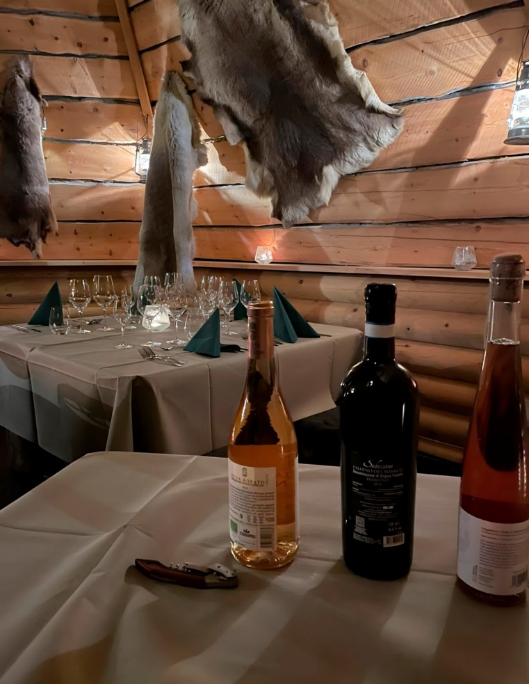 2 tables: one with bottles of exclusive wine and one with wine glasses and skillfully folded napkins